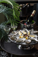 Fresh oysters on a platter in ice with a slice of lemon and spicy sauce.