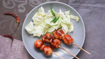 Grilled fermented pork and sticky rice sausage in a gray plate.