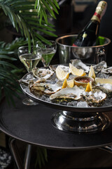 Oysters on ice with lemon slices and spicy sauce on a large platter.