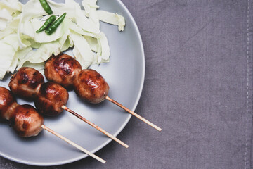 Grilled fermented pork and sticky rice sausage in a gray plate.