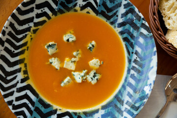 Healthy creamy carrot soup served with soft blue cheese gorgonzola