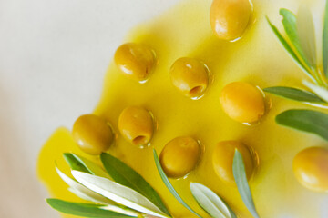 Olives and olive oil.Green olives and olive branch in olive oil in a gray plate close-up .Cold Pressed Organic Natural Oil
