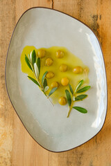 Olives and olive oil.Green olives and olive branch in olive oil in a ceramic gray plate close-up on...