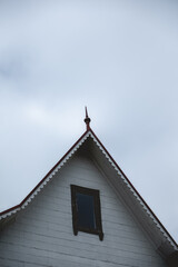Top of a old centuries white wood house with a little window, red roof and old antenna (antiquitech) in a cloudy day, Valdivia, Chile 
