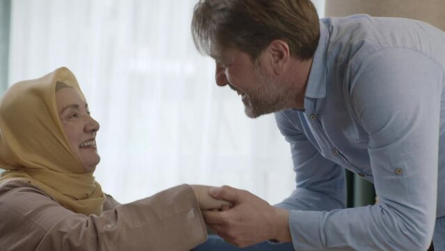 Young man kisses his mother's hand during Eid Mubarak (Turkish Ramadan or Şeker Bayram). The man kisses her hand to show respect to her veiled mother. Muslim holiday traditions concept.