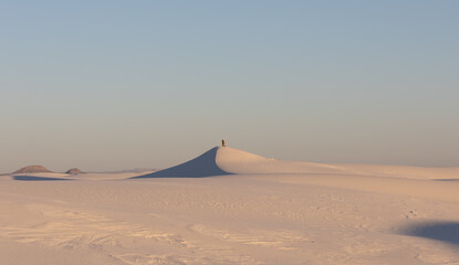 Fototapeta na wymiar Couple on top of a sand dune at sunset in White Sands National Park