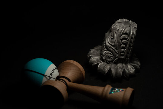 kendama toy next to a Quetzalcoatl feathered serpent on black background