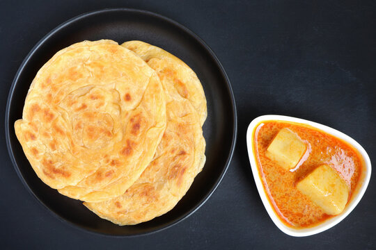 Roti Parata Or Roti Canai Served With Potato Curry Sauce On Black Background.Top View.