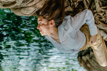 Mujer acostada en las raíces de un árbol junto a un lago