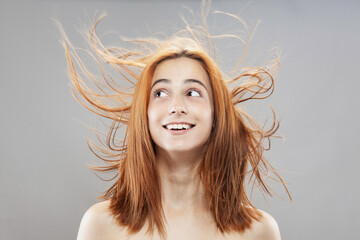 Beautiful dark burnt orange windy hair girl smiling. Studio portrait with happy face expression...