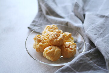 The eclair is placed in a glass dish on a white table.