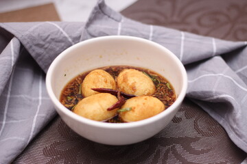 Egg with Tamarind Sauce in a white plate served on a wooden table with coriander sprinkles, is a popular local dish that Thai people eat.