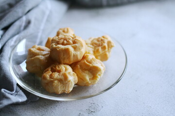 The eclair is placed in a glass dish on a white table.