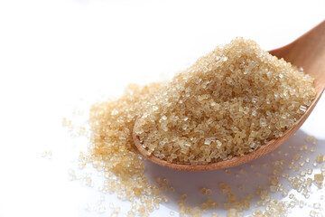 Close up of brown sugar in wooden spoon isolated on white background. Top view. 