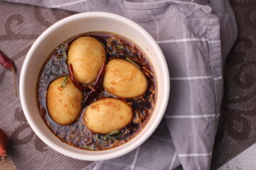 Egg with Tamarind Sauce in a white plate served on a wooden table with coriander sprinkles, is a popular local dish that Thai people eat.