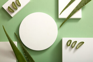 Top view view of aloe vera decorated with white podium in green background 