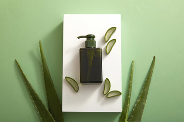 Top view of white podium with aloe vera and cosmetic jar in green background 