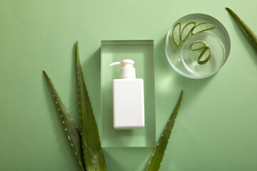 Top view of white podium with aloe vera and cosmetic jar in green background 