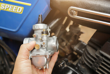 mechanic hand hold new carburetor for change in old car using for good running. motorcycle...