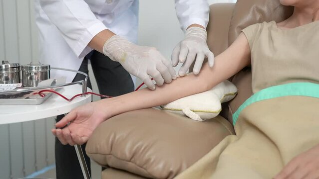 Doctor removes tape from blood donor arm. Volunteer at the blood donation center.