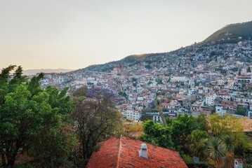 Fototapeta na wymiar City in the evening light mountainside with colonial architecture, many white houses with tiles. Evening sky. The cramped streets of Taxco in Mexico