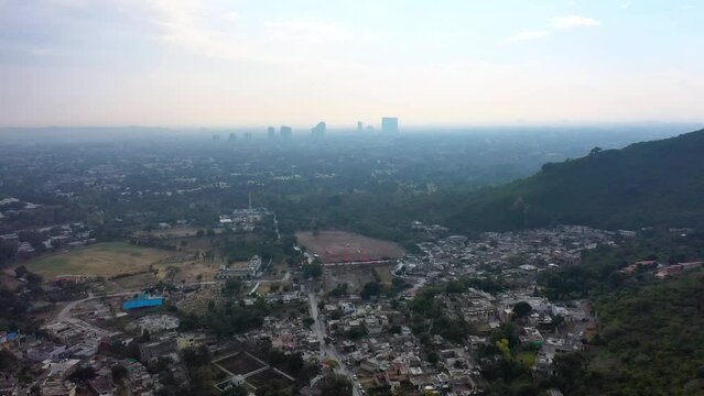 Aerial Slowly Moving Forward Over A Sprawling City On A Hazy Morning With Highrise Towers In The Distance - Islamabad, Pakistan