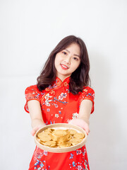 Portrait of Young asian woman wearing traditional cheongsam qipao dress showing Gold ingot and coins meaning 