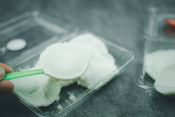 Man is eating Thai coconut milk custard in small porcelain cup.