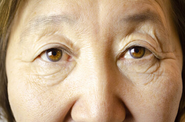 Old asian woman with brown eyes. Eyes with wrinkles. 