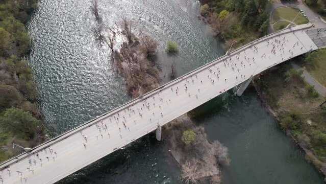 people running on bridge over river