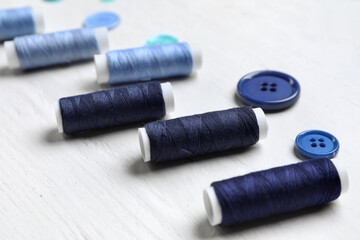 Sewing threads on light wooden background, closeup
