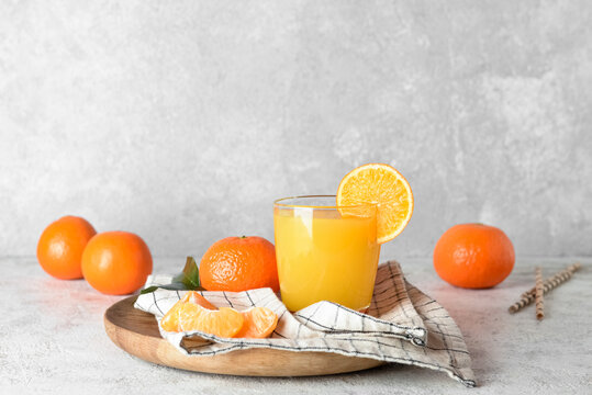 Glass of fresh tangerine juice on light background