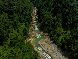 Aerial drone view of falling water from high angle view at Lata Berangin Waterfall, Kuala Krai, Kelantan, Malaysia.