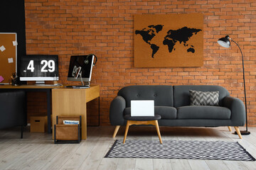 Interior of stylish room with comfortable sofa and modern workplace near brick wall
