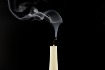 White candle extinguished on black background