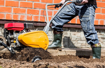 Banner. A male farmer plows the land with a cultivator. Agricultural machinery for tillage in the...