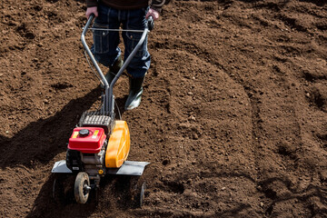 Banner. A male farmer plows the land with a cultivator. Agricultural machinery for tillage in the...