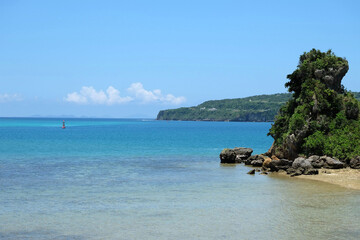 Fototapeta premium 透き通るような青い海と夏の青い空、近くの小さい島と遠くの木々に囲まれた島