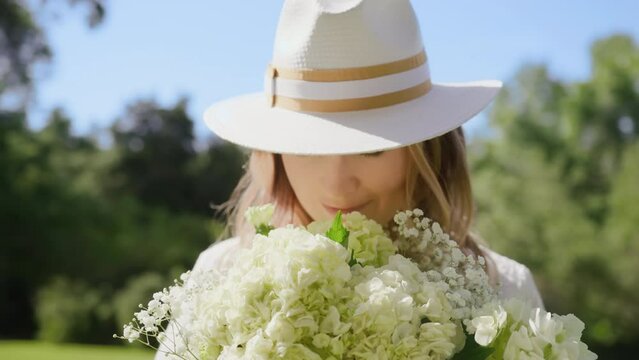 RED camera slow motion portrait beautiful woman smelling gentle white flowers. Close Up smiling lady face with fresh spring flower bouquet in sunlight. Face of happy girl enjoying summer. Video series