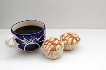 Fresh, delicious and fluffy Mexican bread Manteconchas cupake type vanilla and chocolate flavor accompanied by coffee on a white background traditional of the culture of Mexico
