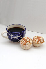 Fresh, delicious and fluffy Mexican bread Manteconchas cupake type vanilla and chocolate flavor accompanied by coffee on a white background traditional of the culture of Mexico
