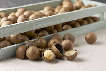 macadamia nuts in a vintage wooden box next to scattered nuts