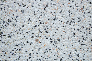 Textured surface close up. Grey background. The wall is made of cement, black, grey and  brown small stones. Eco-friendly concept of using  natural materials in design and everyday life. 