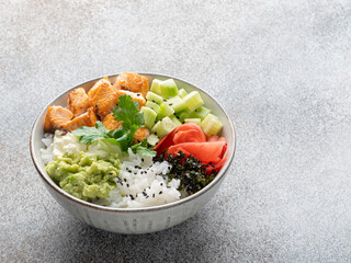 Salmon poke (buddha bowl) with avocado puree, cucumber cubes, pickled ginger, dry nori seaweed, cream cheese, sesame seeds and rice. Healthy seafood dish, lunch or dinner. Closeup view. Copy space.