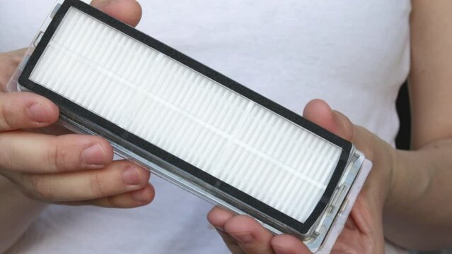 Air filter for robot vacuum cleaner close up 4k video. woman, girl, young female is holding close to camera an air filter for robot vacuum mop cleaner. replacement