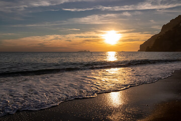 Panoramic sunset view from Marina Grande beach in Positano at Amalfi Coast, Italy, Campania, Europe. Silhouette of coastline. Orange twilight over Li Galli islands in Mediterranean Sea. Reflection