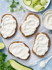 Open sandwiches, rye bread bruschetta with cream cheese spread (ricotta) and cucumber slices on...