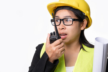 Female civil engineer in a helmet holding construction plans and using walkie-talkie and talk to other staff on a white background in studio.