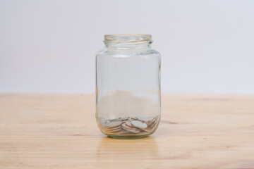 Glass jars with coins on wooden desk. Savings and Investments concept.