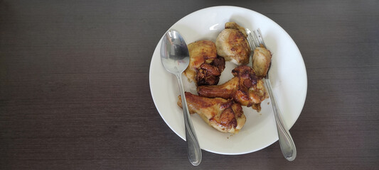 Grilled chicken marinated with spices Ready to eat in a white plate on a black wooden floor. from top view